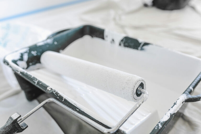 paint roller with tray full of white paint